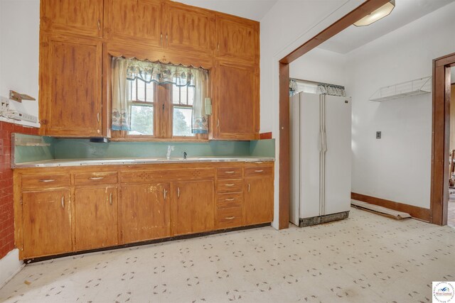 245 Randolph St, Tipton, MO 65081 - kitchen with brown cabinetry, light floors, light countertops, and freestanding refrigerator