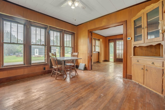 245 Randolph St, Tipton, MO 65081 - dining space featuring wooden walls, ceiling fan, a healthy amount of sunlight, and hardwood / wood-style floors