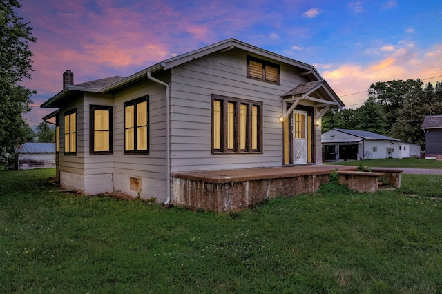 245 Randolph St, Tipton, MO 65081 - back of house at dusk featuring a lawn and a chimney