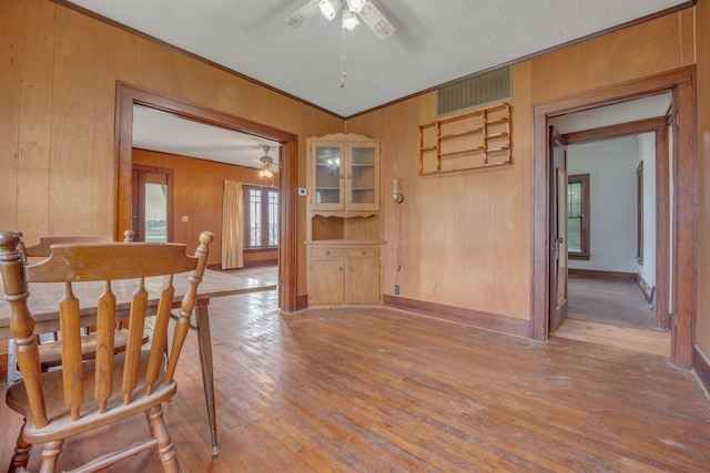 245 Randolph St, Tipton, MO 65081 - dining space featuring wooden walls, hardwood / wood-style flooring, visible vents, and a ceiling fan