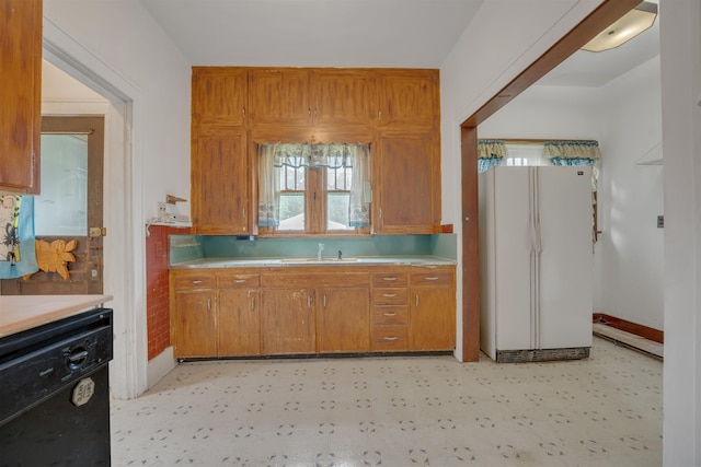 245 Randolph St, Tipton, MO 65081 - kitchen featuring brown cabinets, a sink, black dishwasher, light countertops, and freestanding refrigerator
