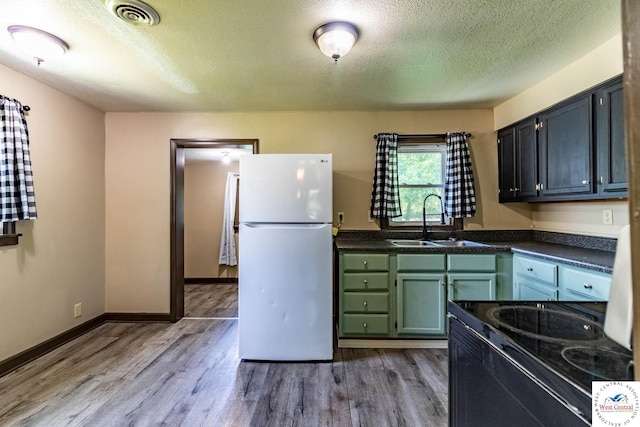806 E Green St, Clinton, MO 64735 - kitchen with freestanding refrigerator, a sink, a textured ceiling, dark countertops, and light wood finished floors