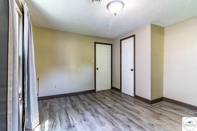 806 E Green St, Clinton, MO 64735 - unfurnished bedroom featuring wood finished floors, a textured ceiling, and baseboards