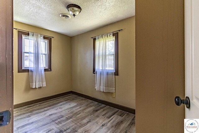 806 E Green St, Clinton, MO 64735 - unfurnished room featuring healthy amount of natural light, a textured ceiling, wood finished floors, and baseboards
