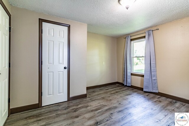 806 E Green St, Clinton, MO 64735 - unfurnished bedroom featuring wood finished floors, a textured ceiling, and baseboards