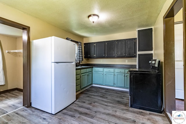 806 E Green St, Clinton, MO 64735 - kitchen featuring freestanding refrigerator, stainless steel electric stove, dark countertops, a textured ceiling, and dark wood-style flooring