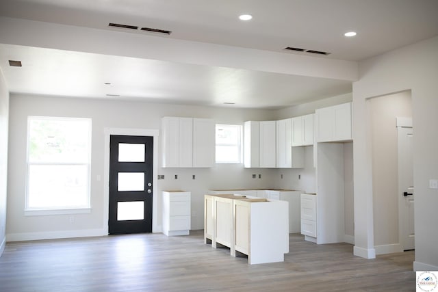 1927 E 6th St, Sedalia, MO 65301 - kitchen with baseboards, white cabinets, light wood-type flooring, a center island, and recessed lighting