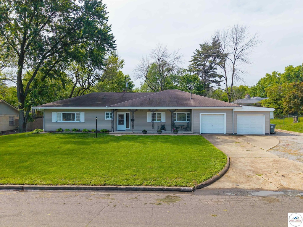 single story home featuring a front lawn, a garage, concrete driveway, and a porch