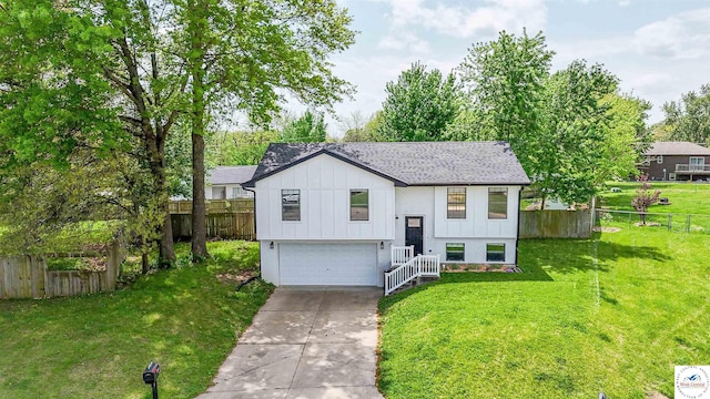 raised ranch featuring an attached garage, a front lawn, board and batten siding, and driveway