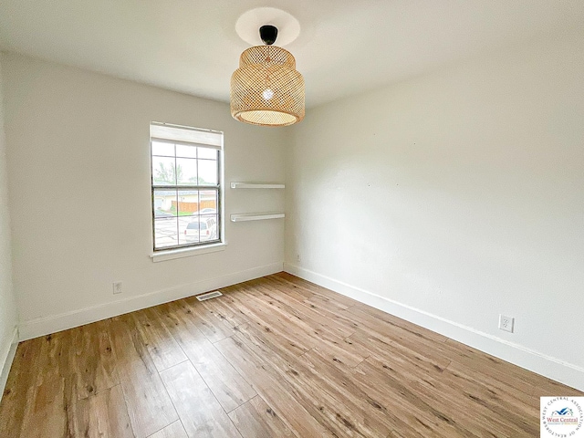 spare room with baseboards, light wood finished floors, and visible vents