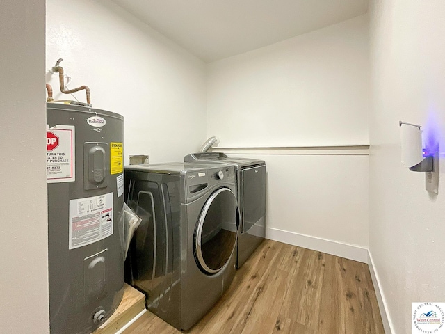 clothes washing area featuring independent washer and dryer, laundry area, water heater, baseboards, and light wood-type flooring