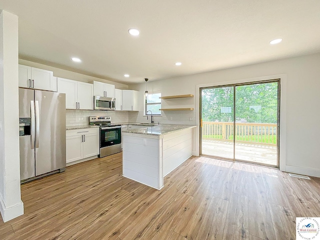 kitchen with light wood-type flooring, white cabinetry, tasteful backsplash, a sink, and stainless steel appliances