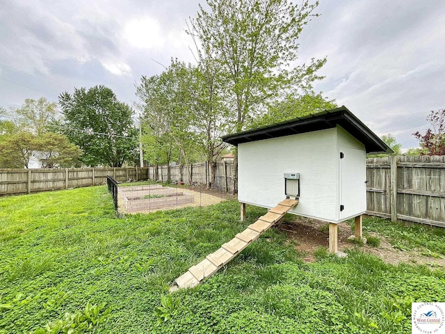 view of yard featuring an outbuilding, a fenced backyard, and a vegetable garden