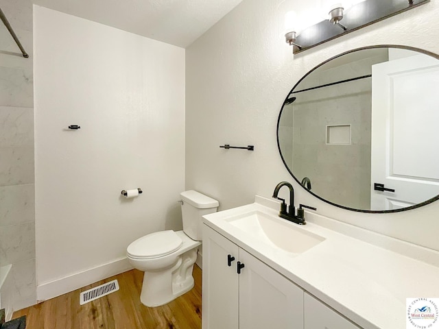 full bathroom with visible vents, vanity, wood finished floors, toilet, and walk in shower