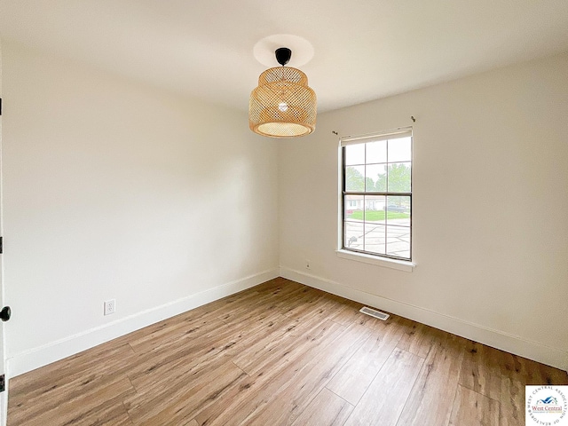 unfurnished room featuring baseboards, light wood-style flooring, and visible vents