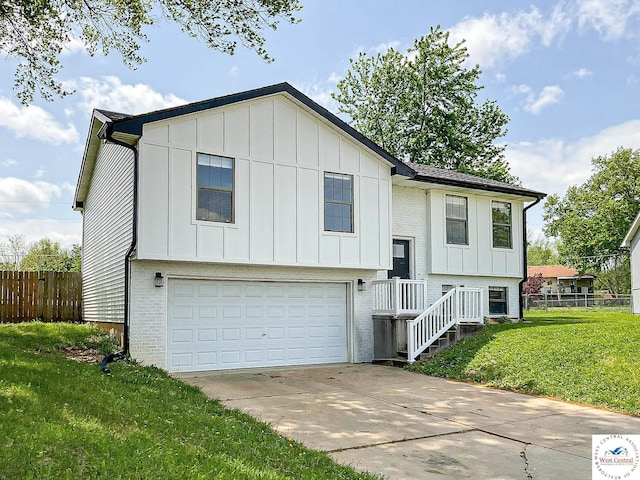 split foyer home featuring an attached garage, board and batten siding, and fence