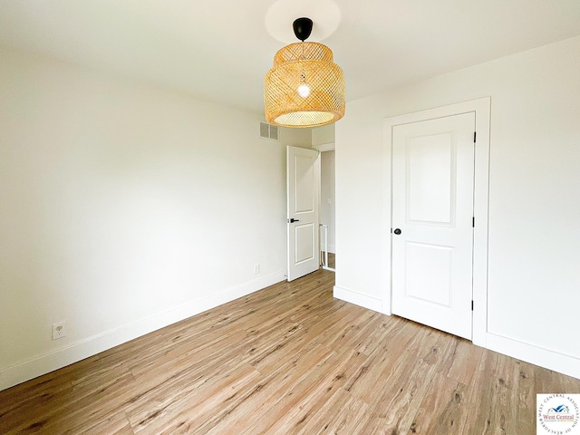 empty room with light wood-style floors, baseboards, and visible vents