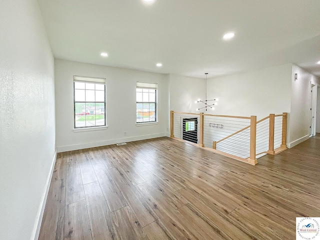 unfurnished living room featuring recessed lighting, baseboards, a chandelier, and wood finished floors