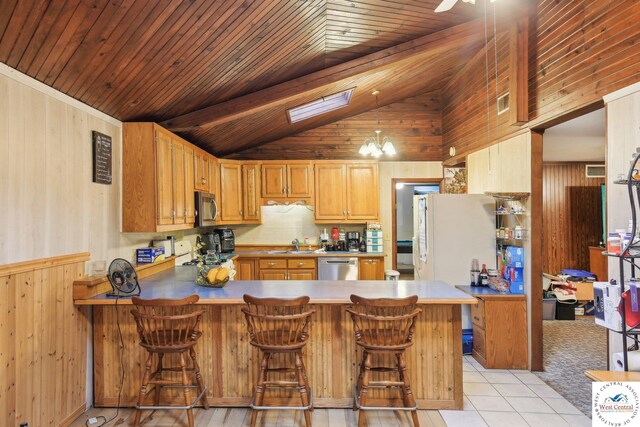 828 SE 601st Rd, Leeton, MO 64761 - kitchen with stainless steel appliances, a sink, a peninsula, wood walls, and light tile patterned floors
