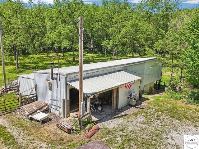 828 SE 601st Rd, Leeton, MO 64761 - view of side of property featuring a pole building, an outdoor structure, and a view of trees