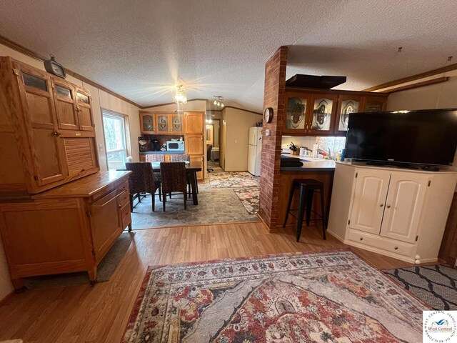 31674 Aspen Rd, Stover, MO 65078 - kitchen with light wood-style floors, freestanding refrigerator, glass insert cabinets, lofted ceiling, and a textured ceiling