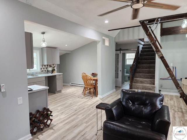 10075 Otter Rd, Clinton, MO 64735 - living room featuring a baseboard heating unit, a ceiling fan, light wood-type flooring, a barn door, and baseboards
