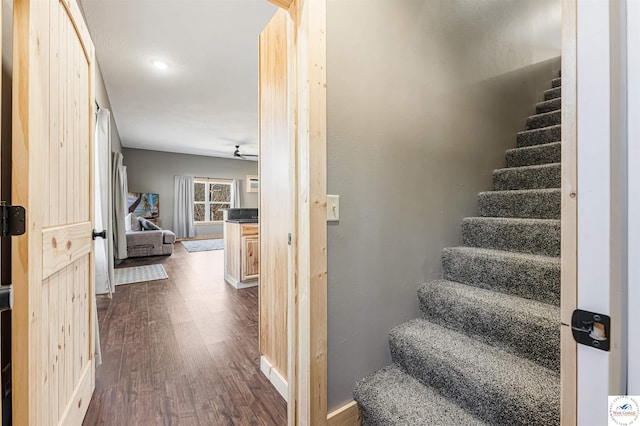 stairway featuring baseboards, wood finished floors, and a ceiling fan