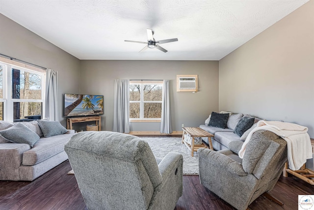 living area featuring a ceiling fan, a wall mounted AC, a wealth of natural light, and dark wood finished floors