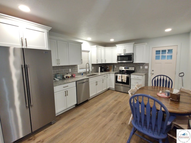 29790 Bobcat Dr, Warsaw, MO 65355 - kitchen with stainless steel appliances, a sink, backsplash, light wood-type flooring, and white cabinetry