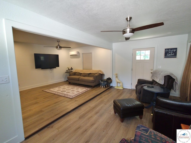 29790 Bobcat Dr, Warsaw, MO 65355 - living area featuring a ceiling fan, a wall mounted AC, wood finished floors, a textured ceiling, and baseboards