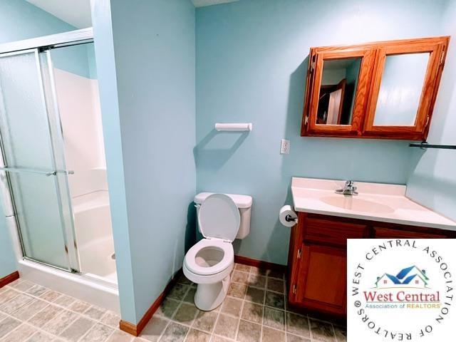 bathroom featuring baseboards, a stall shower, and vanity
