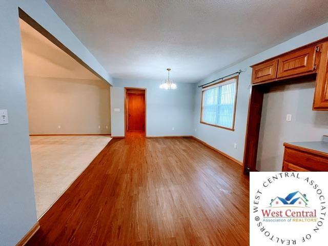 interior space with baseboards, an inviting chandelier, and light wood-style floors