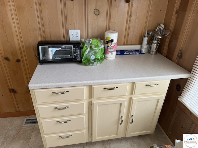 19094 Kennedy Rd, Warsaw, MO 65355 - kitchen featuring light countertops, wood walls, cream cabinetry, and light tile patterned floors