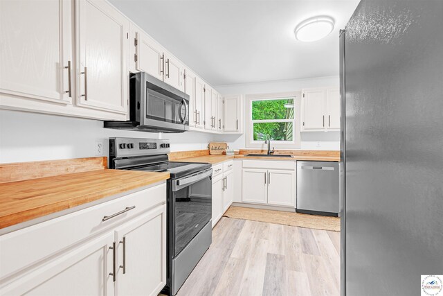 1803 S Quincy Ave, Sedalia, MO 65301 - kitchen featuring appliances with stainless steel finishes, a sink, light wood-style floors, and white cabinets