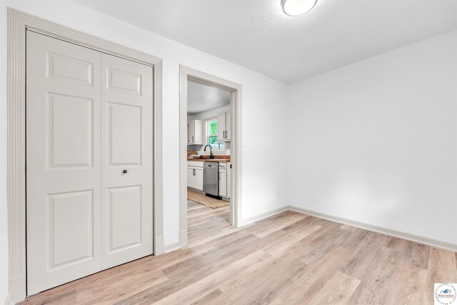 1803 S Quincy Ave, Sedalia, MO 65301 - spare room featuring light wood-style flooring, baseboards, a sink, and a textured ceiling