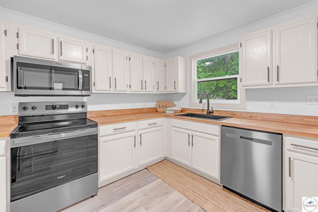 1803 S Quincy Ave, Sedalia, MO 65301 - kitchen with appliances with stainless steel finishes, a sink, butcher block counters, light wood-type flooring, and white cabinetry