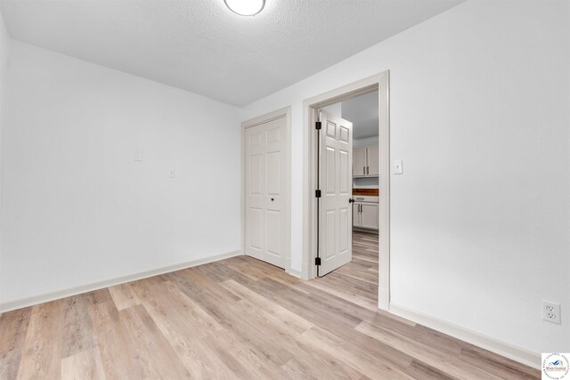 1803 S Quincy Ave, Sedalia, MO 65301 - spare room with light wood-style flooring, baseboards, and a textured ceiling