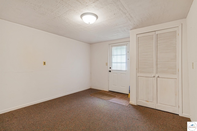 doorway to outside with carpet floors, a textured ceiling, and baseboards