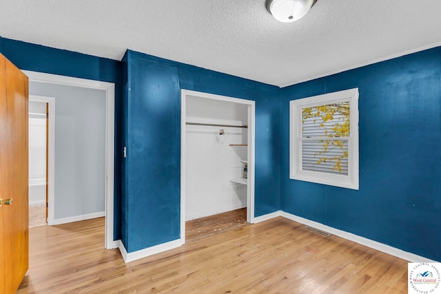 6204 E 147th Ter, Grandview, MO 64030 - unfurnished bedroom with wood finished floors, a textured ceiling, a closet, and baseboards