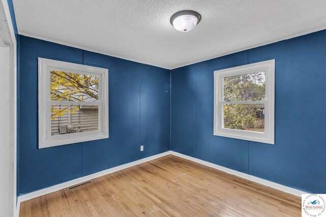 6204 E 147th Ter, Grandview, MO 64030 - unfurnished room featuring a textured ceiling, wood finished floors, ornamental molding, and baseboards