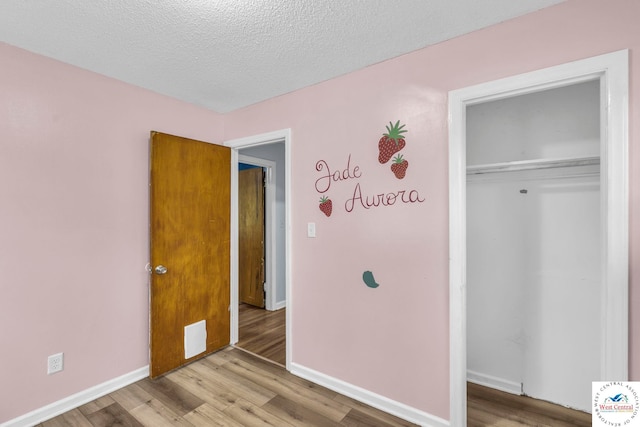 6204 E 147th Ter, Grandview, MO 64030 - unfurnished bedroom with wood finished floors, a closet, baseboards, and a textured ceiling
