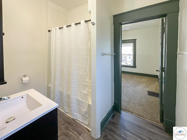 bathroom with vanity, curtained shower, visible vents, baseboards, and wood finished floors