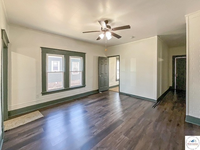 spare room featuring crown molding, dark wood-style floors, a ceiling fan, and baseboards