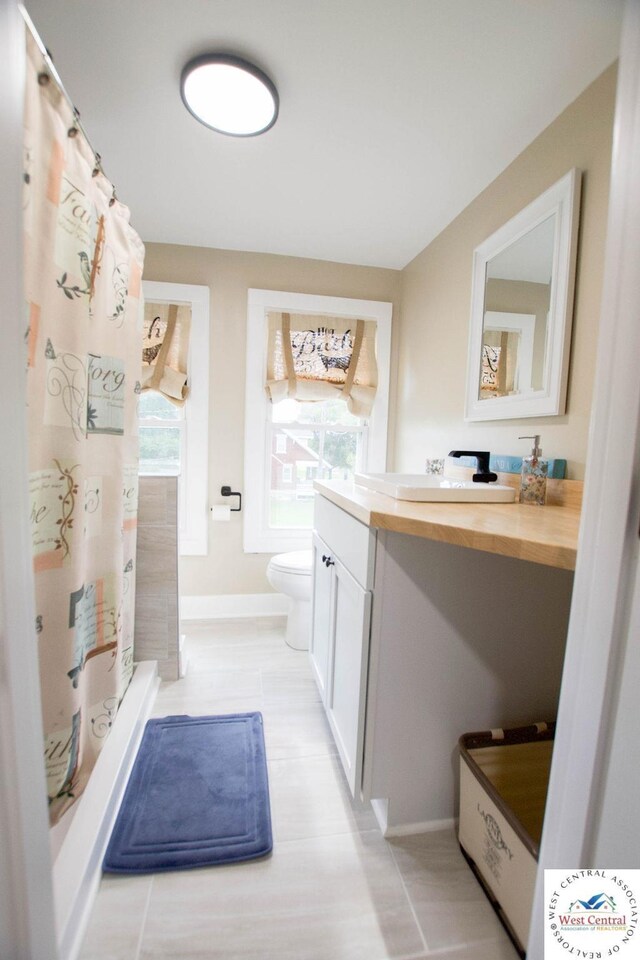 1625 W 16th St, Sedalia, MO 65301 - full bathroom featuring vanity, toilet, a shower with curtain, and baseboards