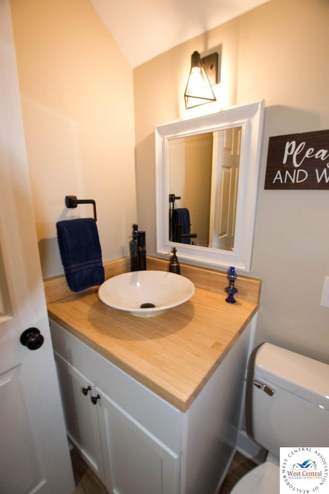 1625 W 16th St, Sedalia, MO 65301 - half bathroom with vanity, toilet, and vaulted ceiling