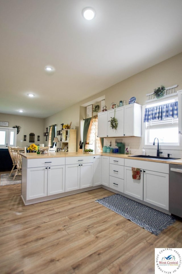 1625 W 16th St, Sedalia, MO 65301 - kitchen with dishwasher, a sink, a peninsula, white cabinets, and light wood-style flooring