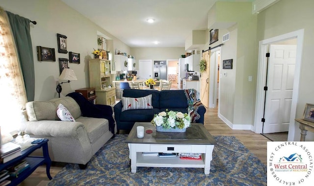 1625 W 16th St, Sedalia, MO 65301 - living room featuring wood finished floors, a barn door, and baseboards