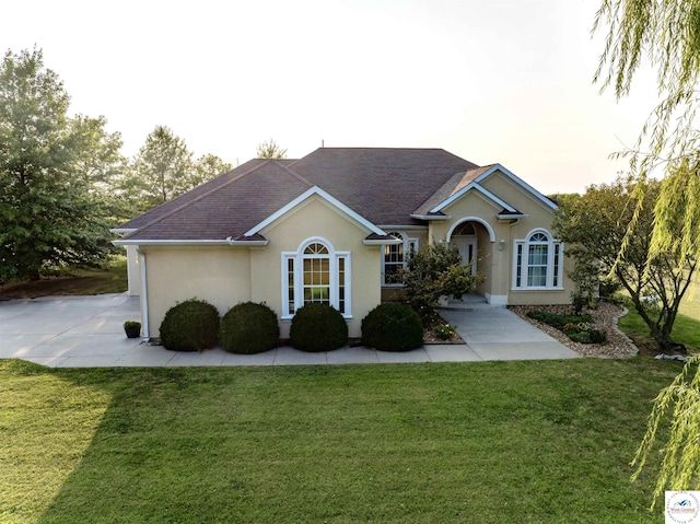 ranch-style house featuring stucco siding, roof with shingles, and a front lawn