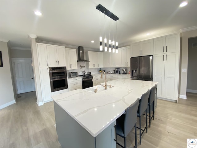 kitchen with a sink, baseboards, black appliances, ornamental molding, and wall chimney exhaust hood