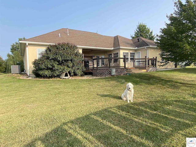 back of house with stucco siding, a yard, and a deck